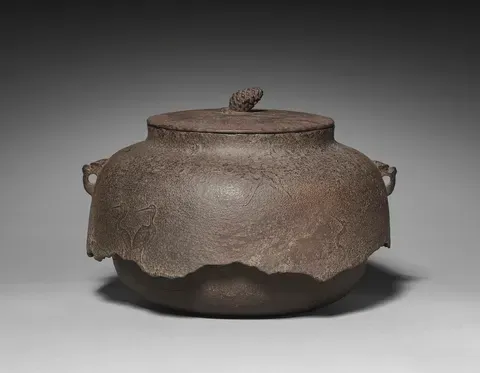 A Muromachi iron kettle with a lobed body and small side lugs, cranes cast into its skin